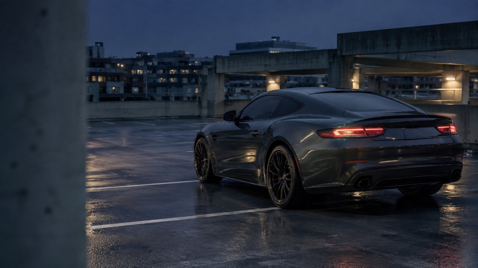 Finished graphite coupe reflecting blue-hour light on wet concrete